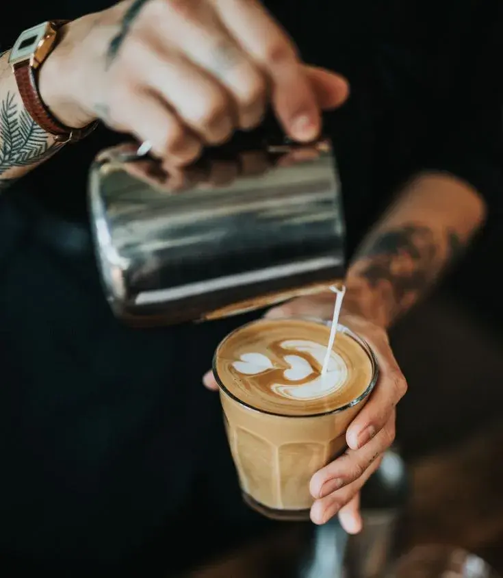 Tattooed barista pouring latte art