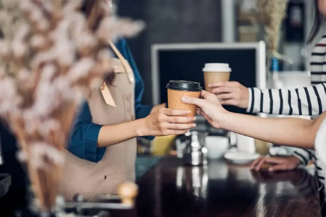 Barista handing over a fresh coffee at the counter